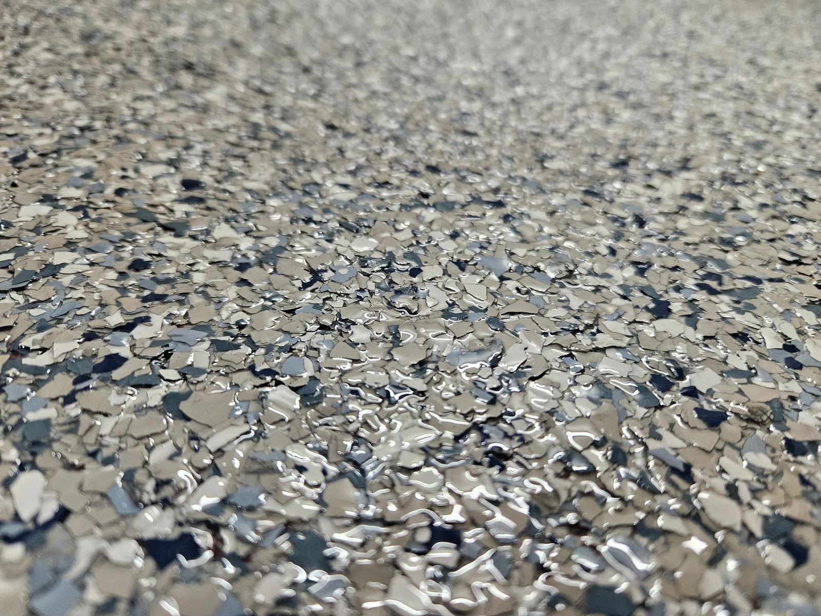 Close-up of grey, white and black vinyl flake sealed under a clear topcoat